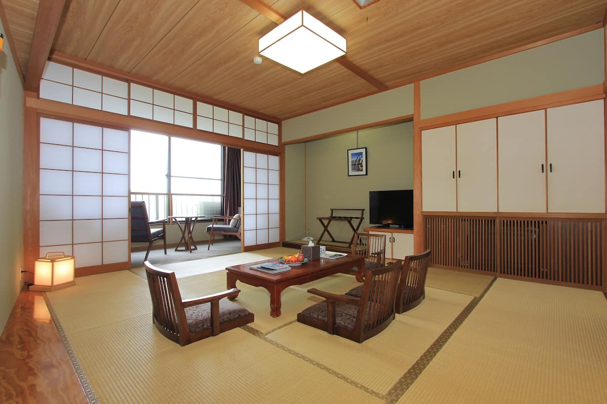 Ein traditioneller japanischer Raum mit Tatami-Bodenbelag, einem niedrigen Holztisch und einem Fernseher.