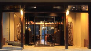 Ein Hotel mit Eingangsbereich, einer Glastür und Innenbereich mit Sitzgelegenheiten. Zwei Wandleuchten sind angebracht.