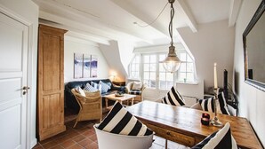 Ein Essbereich mit einem Holztisch, gestreiftem Kissen und einer Chandelüster.