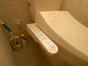 A toilet with a control panel featuring multiple buttons and a foot pedal. - AMS TOWER Nakajima (Sapporo)