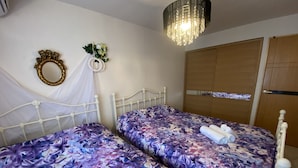 Une chambre avec deux lits, un lustre, un miroir et une armoire.