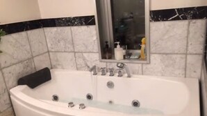 Une salle de bain avec une grande baignoire, un miroir au-dessus du lavabo et un mur recouvert de carreaux formant un motif noir et blanc.