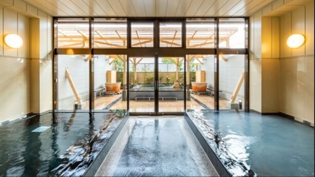 Un área de piscina interior moderna con puertas de cristal que dan a un espacio exterior.