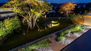 Un jardín ajardinado con árboles y una fuente al anochecer.