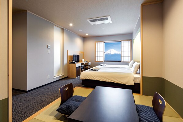 Habitación de hotel con cama, escritorio, silla y vistas a la montaña.