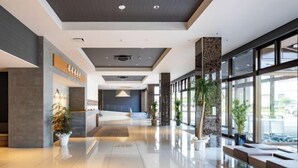 Un moderno vestíbulo de hotel con mostrador de recepción, zona de estar y grandes ventanales que ofrecen vistas al exterior.