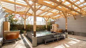 Una estructura de madera con techo de vidrio, un jacuzzi y un camino de piedra.