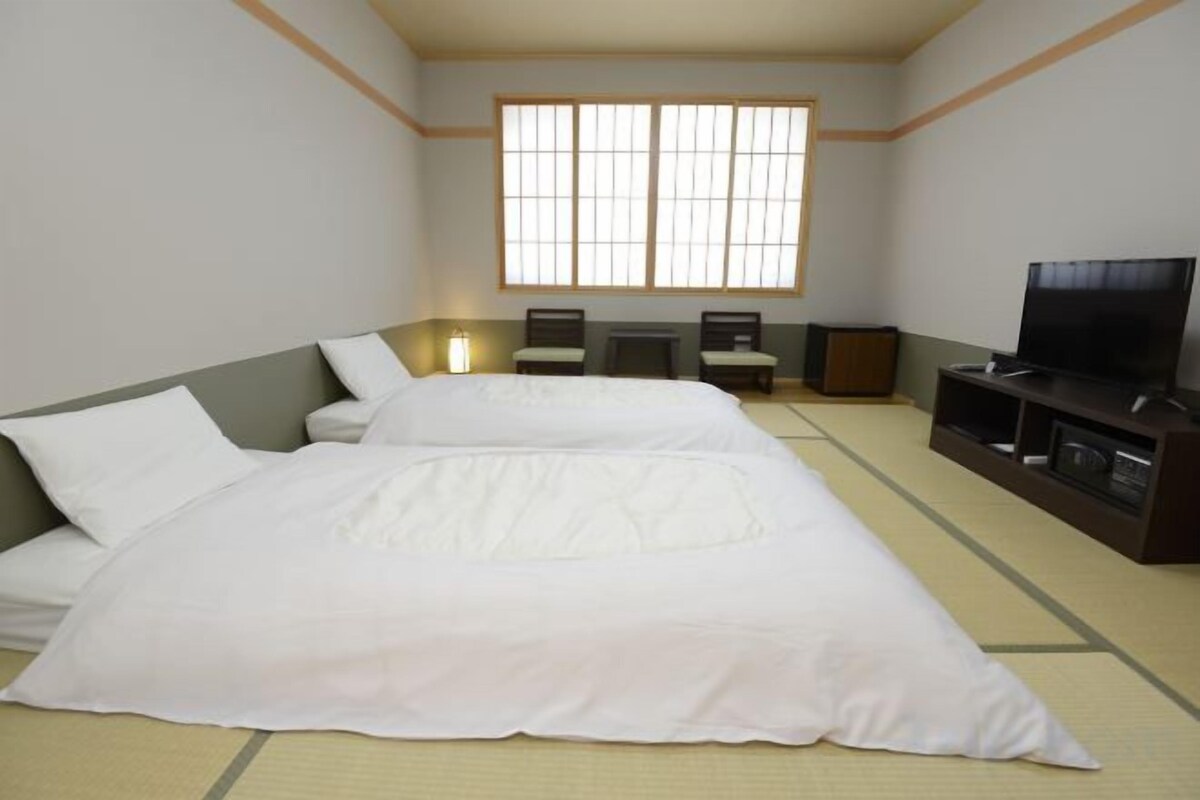 A hotel room with a large bed, a television, and a window with a view.