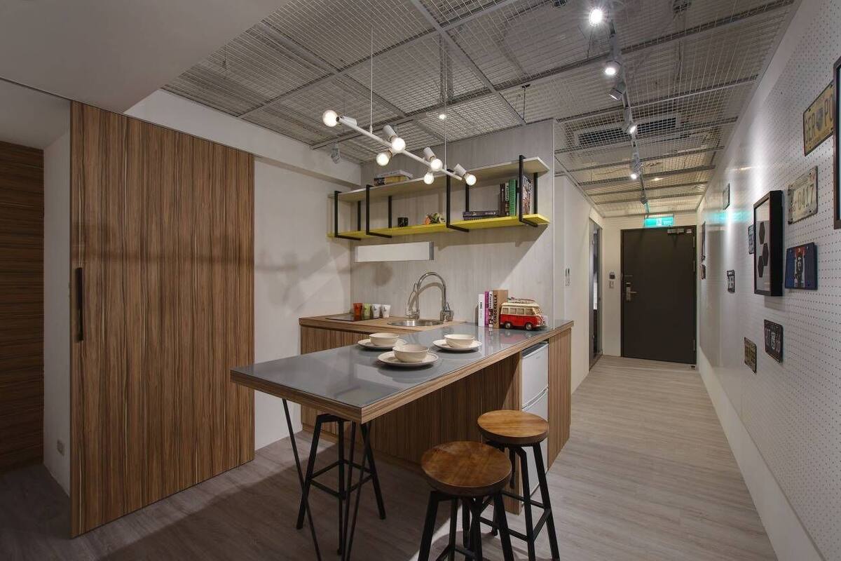 A modern kitchen with a central island, bar stools, and a hanging light fixture.