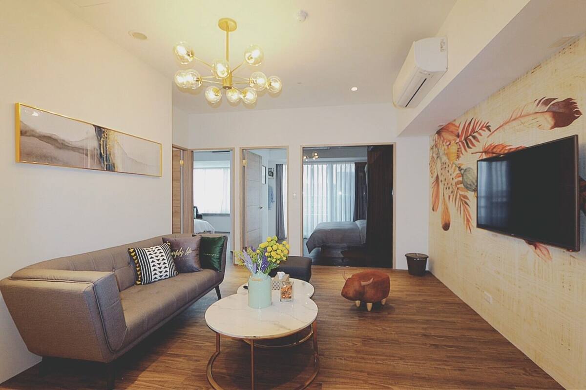 A modern living room with a sofa, a coffee table, a TV, and a decorative wall.