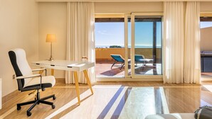 Une chambre d’hôtel équipée d’un bureau, d’une chaise et offrant une vue sur le balcon et son espace salon extérieur.