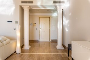 A hallway with a marble floor, white walls, and a door at the end.