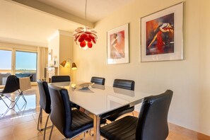 Een moderne eetruimte met een glazen tafel, zwarte leren stoelen en een unieke rode hanglamp.