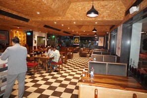 Un interior de restaurante con suelo de madera, varias áreas de estar y lámparas colgantes.