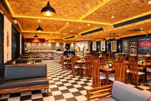 A restaurant interior with a checkered floor, wooden furniture, and pendant lighting. - Hotel Las Vegas (Jaipur)