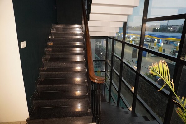 Un escalier en métal noir, doté de rampes en bois, mène à un balcon dont la balustrade est en verre.