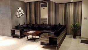 Uma sala de estar moderna com um sofá seccional, uma mesa de centro e um objeto decorativo na parede.