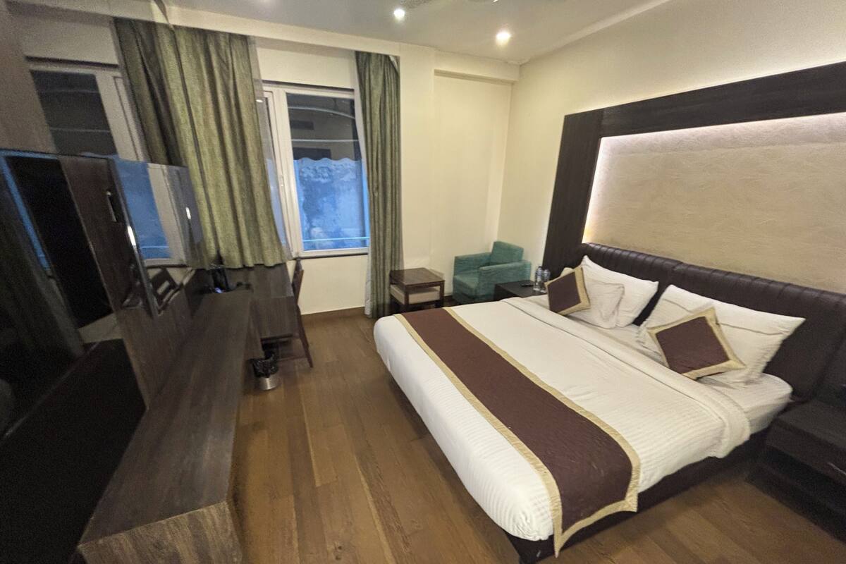 Een hotelkamer met een groot bed, een bureau, een stoel en een televisie.