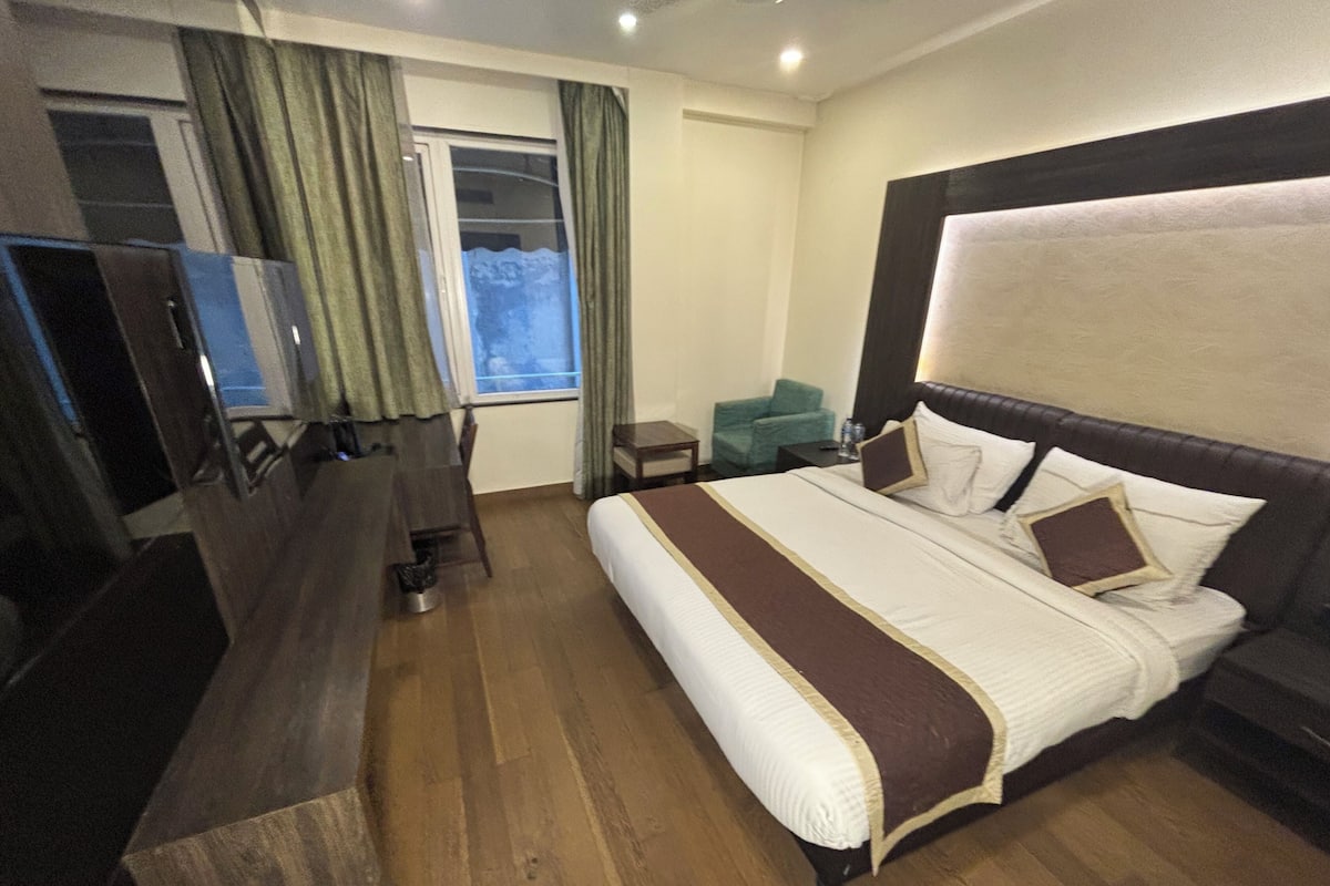 Ein Hotelzimmer mit einem großen Bett, einem Schreibtisch, einem Stuhl und einem Fernseher.