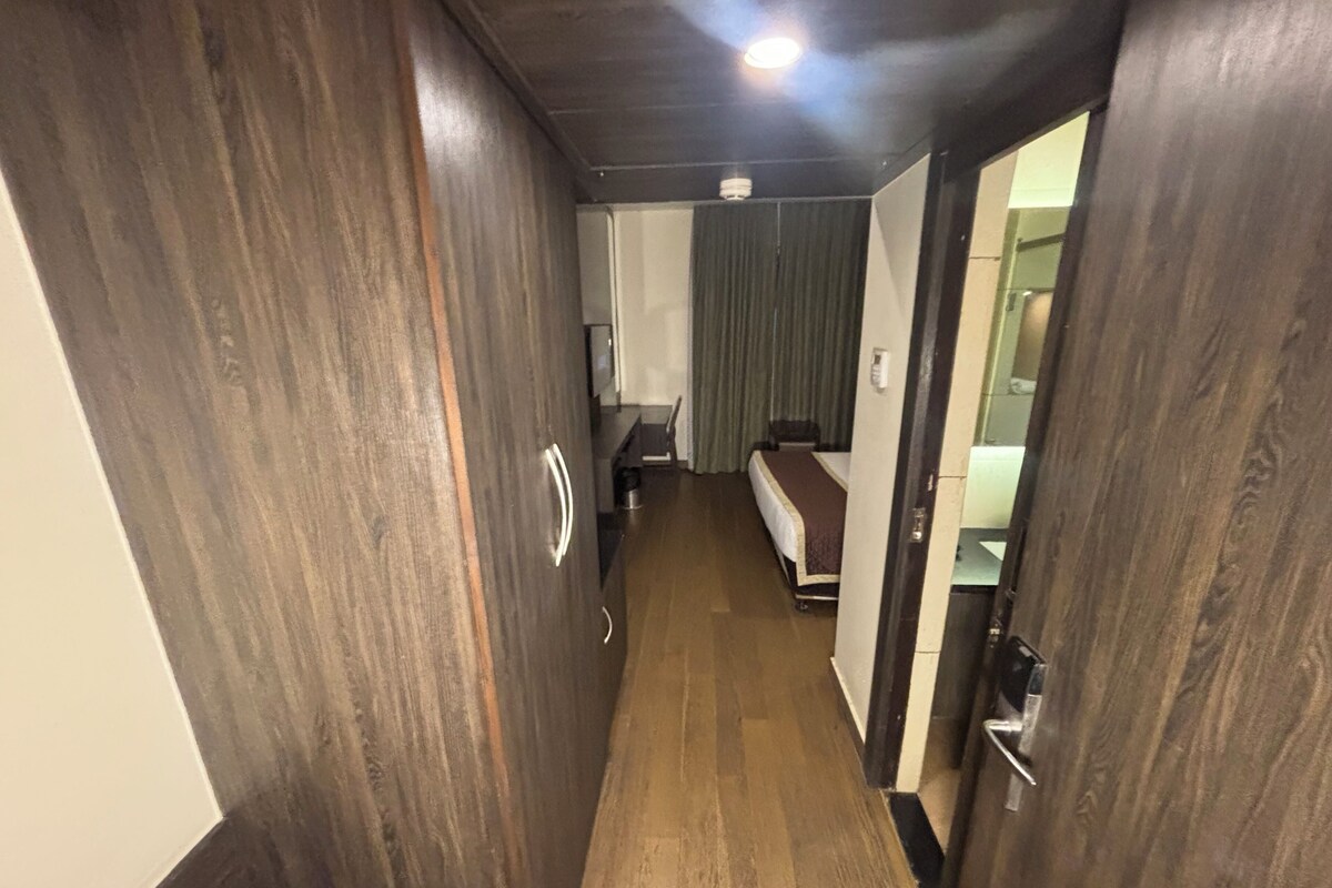 Un pasillo estrecho con suelo de madera que conduce a una habitación con cama y ventana.