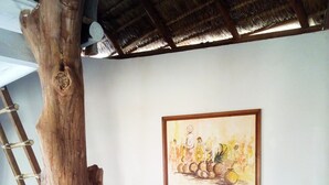 Une pièce avec un banc en bois, un canapé avec des coussins à rayures, une table en bois et un tableau accroché au mur.