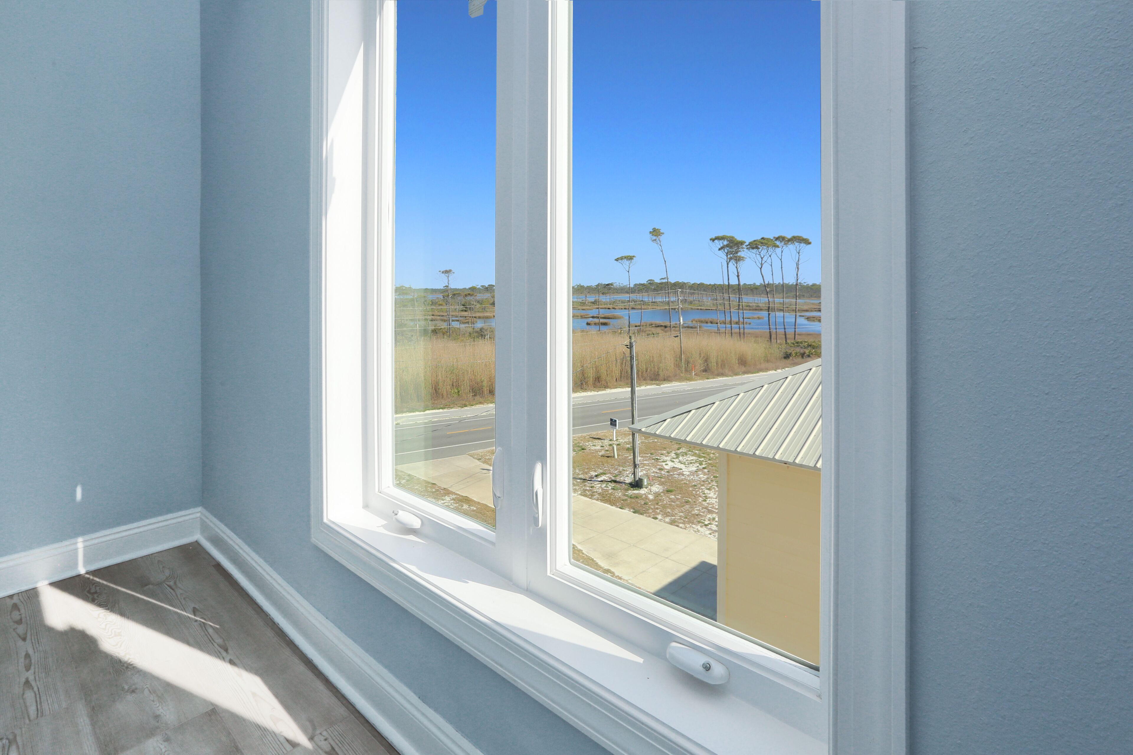 A room with a large window offering a view of a water body and trees.