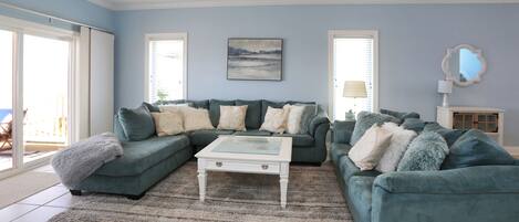 A living room with a sectional sofa, a glass coffee table, and a ceiling fan.