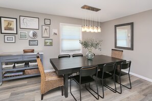 A dining area with a dark wooden table, black chairs, and a hanging light fixture.