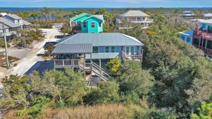A coastal residential area with houses, including a turquoise house with a balcony and a grey house with a porch. - Single Level, Close To Beach, Great Beach View Covered Deck ~ Salt Cured (Cape San Blas)