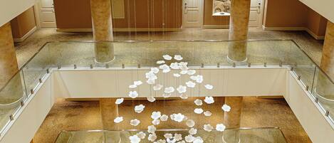 A multi-level hotel lobby with a central atrium, glass railings, and a decorative hanging light fixture.