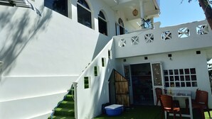A white building with multiple windows and a covered outdoor area with a table and chairs. - OYO 864 Hoang Anh Anh (Ho Chi Minh City)