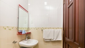 A bathroom with a white sink, a mirror, a towel hanging on the wall, and a wooden door. - OYO 864 Hoang Anh Anh (Ho Chi Minh City)
