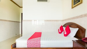 A hotel room with a wooden bed, white bedding, a red throw, and a red pillow with the word "Synergy". - OYO 864 Hoang Anh Anh (Ho Chi Minh City)