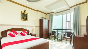 A hotel room with a large bed, a desk, a chair, a wardrobe, and a balcony with a view. - OYO 864 Hoang Anh Anh (Ho Chi Minh City)