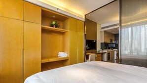 Habitación de hotel con cama, escritorio, televisor y kitchenette.