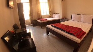 Een hotelkamer met een bed, een bureau, een stoel, een televisie en een raam met gordijnen.