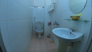 Een kleine badkamer met toilet, wastafel en spiegel.