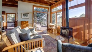 A spacious living room with a wooden ceiling, a fireplace, and large windows offering a view of the outdoors. - Romantic Ridgetop Escape w/ Hot Tub Near Mendocino (Albion)