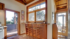 A kitchen with wooden bar stools, a large window, and a view of the outdoors. - Romantic Ridgetop Escape w/ Hot Tub Near Mendocino (Albion)