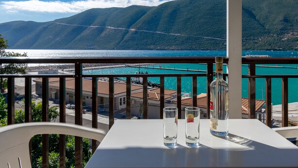Ein Balkon mit Tisch, zwei Gläsern und einer Flasche.