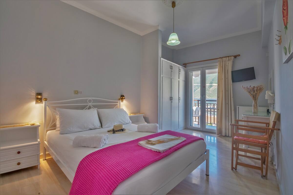 A bedroom with a bed, bedside tables, a desk, and a chair.