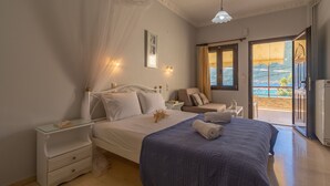 Ein Schlafzimmer mit Bett, Nachttischen, einem Sessel und Blick ins Freie.