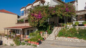 Ein zweistöckiges Gebäude mit einem Balkon, Steinstufen und Topfpflanzen.