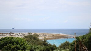 A coastal landscape with a clear view of the ocean, a sandy beach, and a small island in the distance. - Rest and Lodge Syou (Amami)