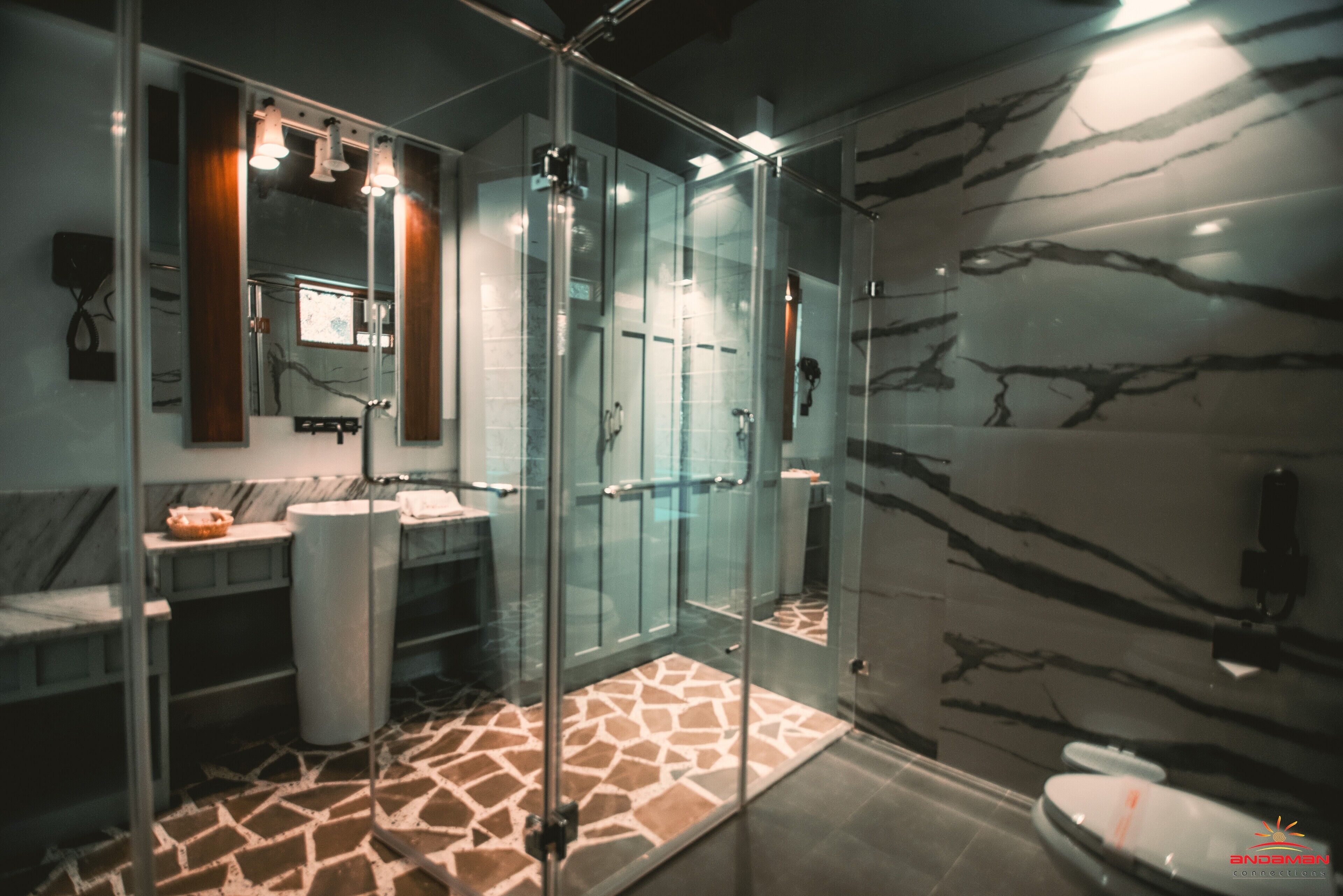 Un baño moderno con cabina de ducha de vidrio, paredes de mármol y suelo estampado.