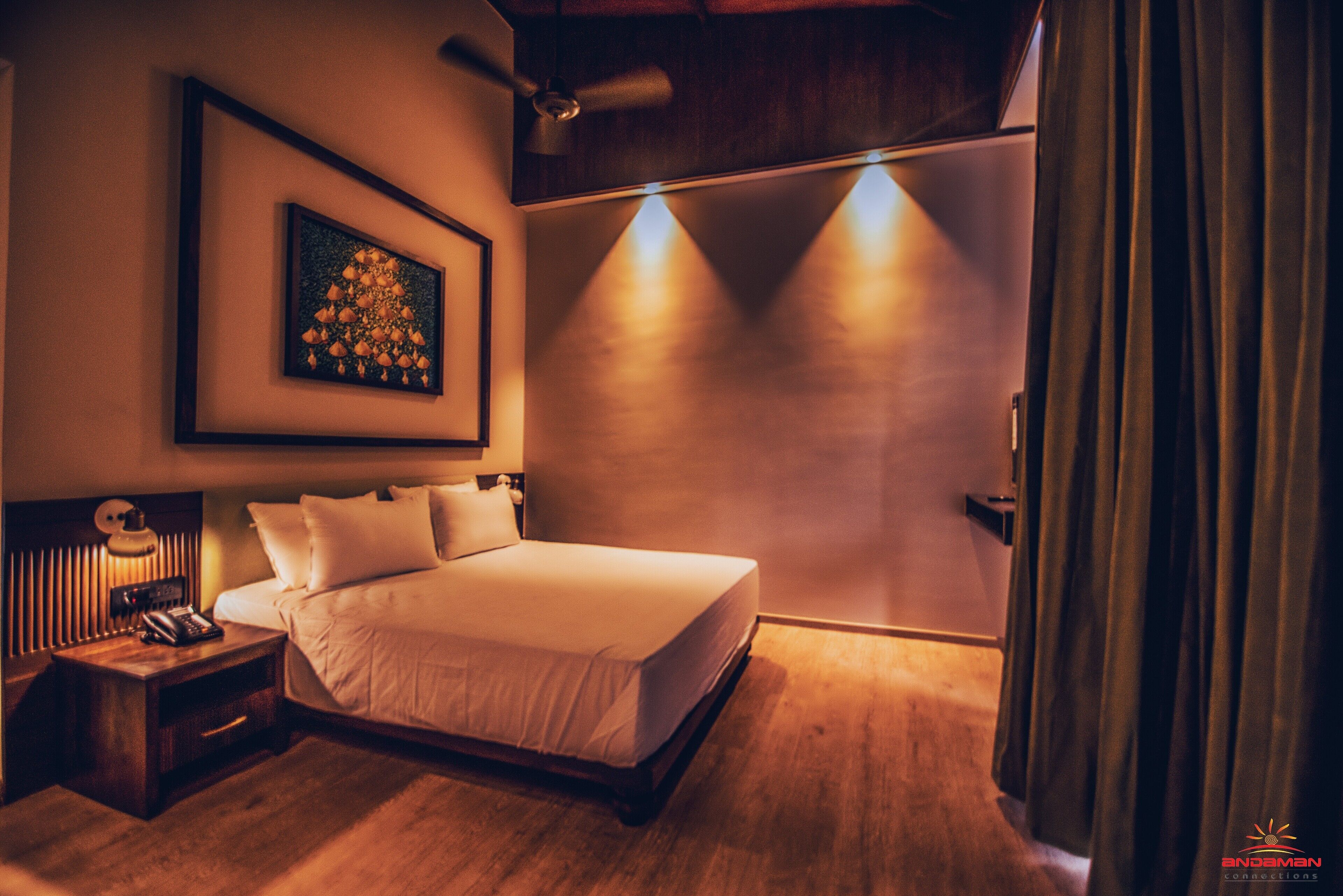 A hotel room with a bed, a nightstand, a framed picture, and a door with curtains.