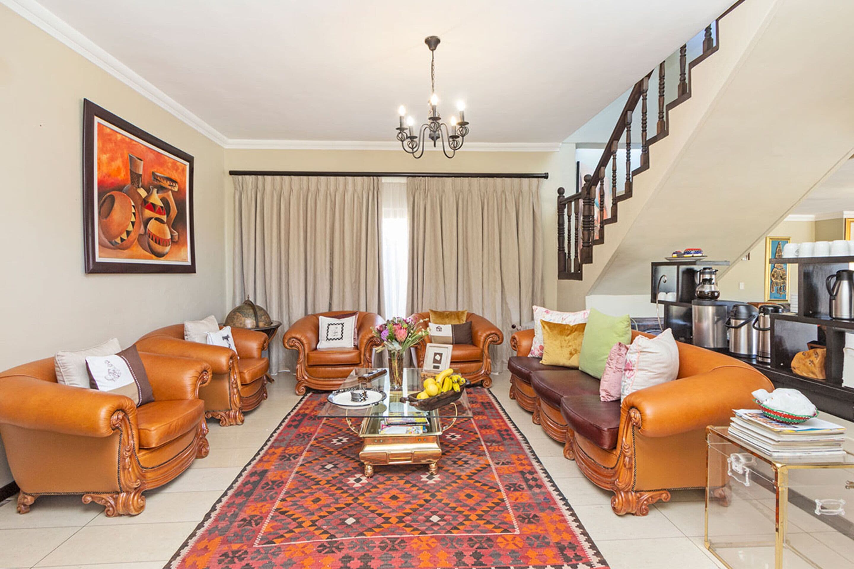 A spacious living room with leather sofas, a coffee table, and a staircase leading to an upper level.