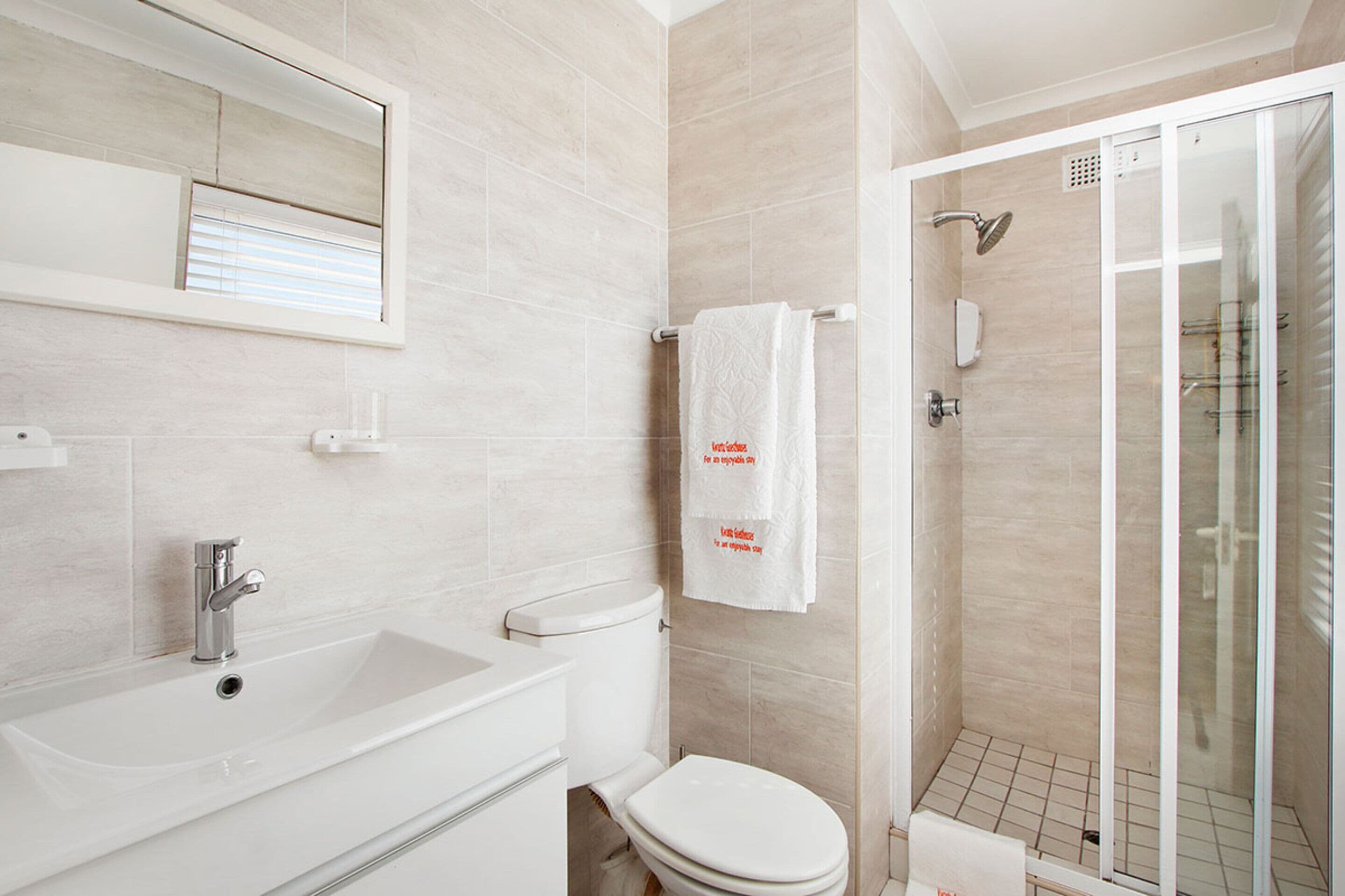 Une salle de bain moderne avec un lavabo, des toilettes et une douche à parois de verre.