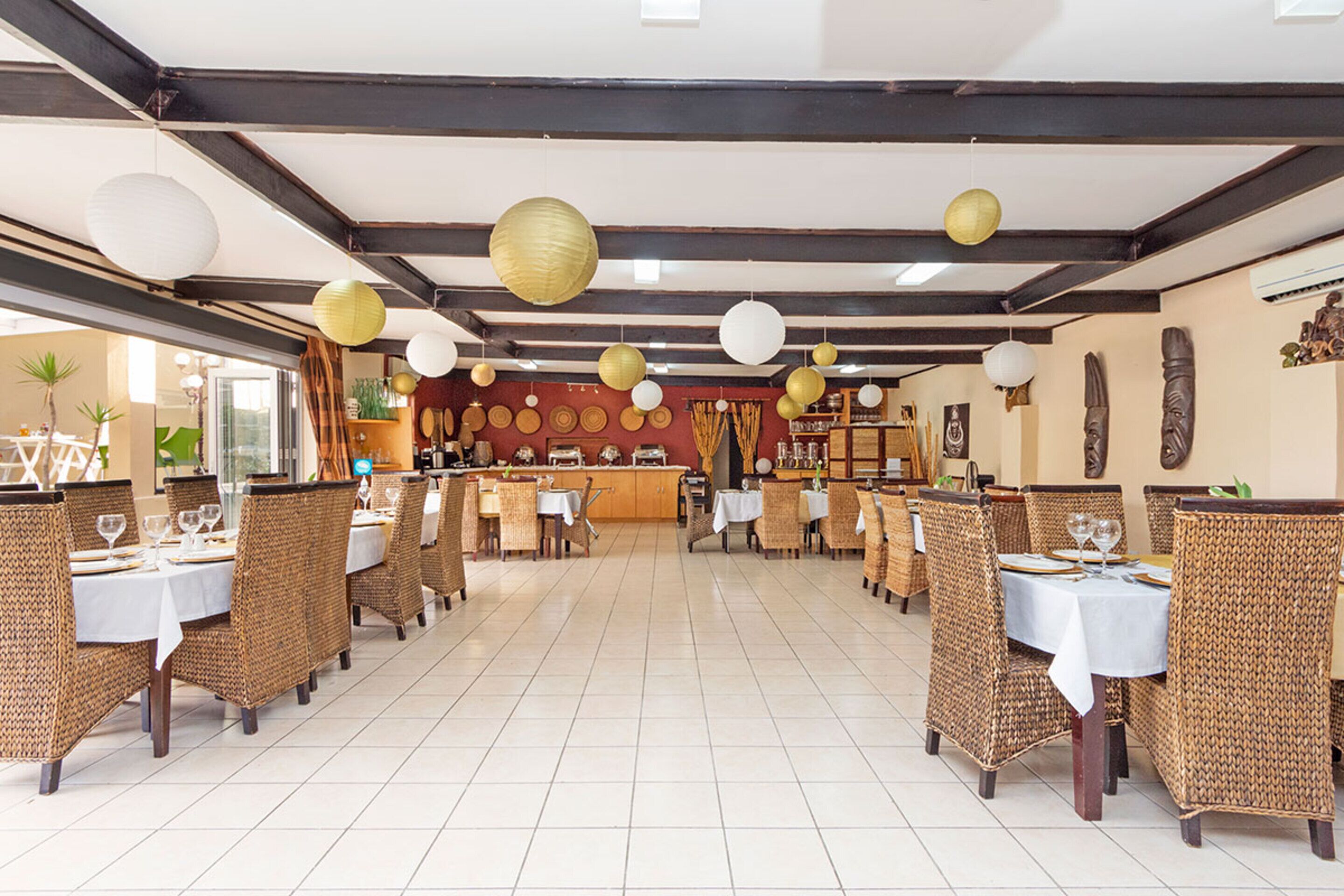 A restaurant with multiple tables and chairs, a tiled floor, and hanging paper lanterns.