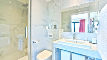 A modern bathroom with a glass shower enclosure, a white toilet, a sink with a mirror, and a towel rack.